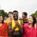 Young diverse people having fun outdoor laughing together - Focus on asian man face